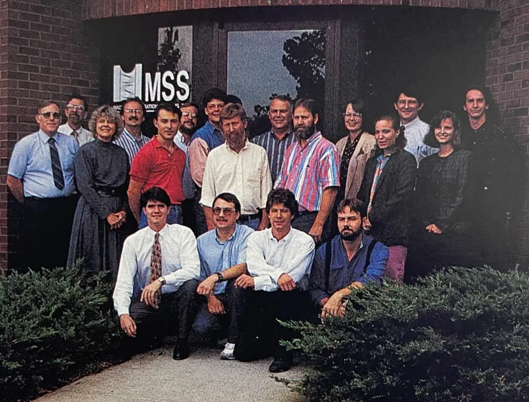 Historical company employee image of MSS team members from the 1990s standing outside the office together