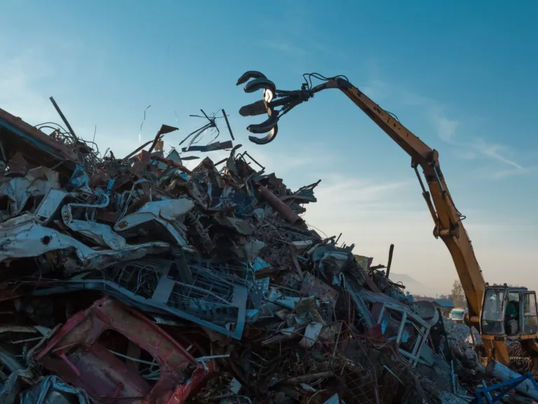 Image of a scrap yard with a tractor grabbing metal pieces from a pile