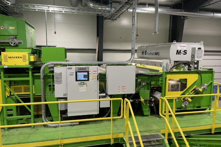 Image of a green PurePlasticMax™ recycling unit on a platform.
