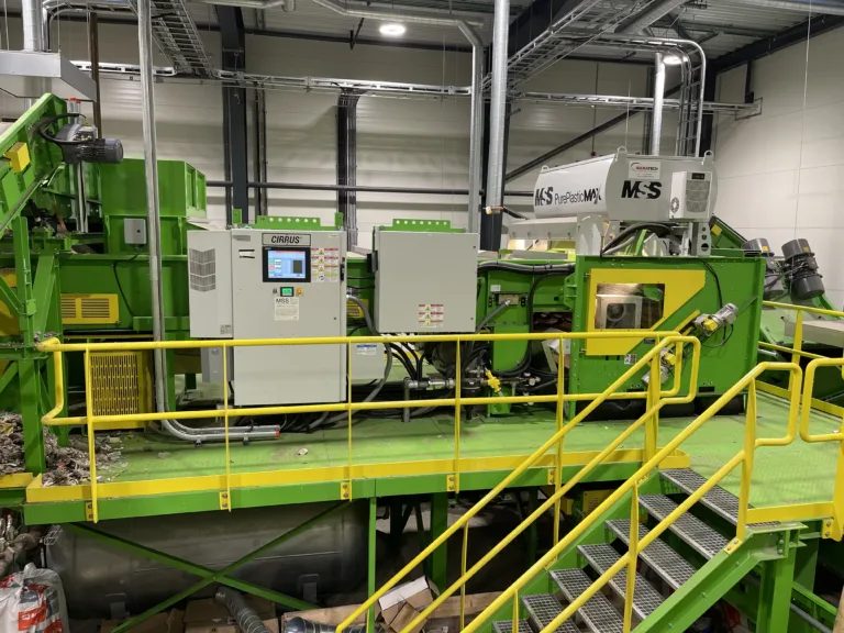 Image of a green PurePlasticMax™ recycling unit on a platform.
